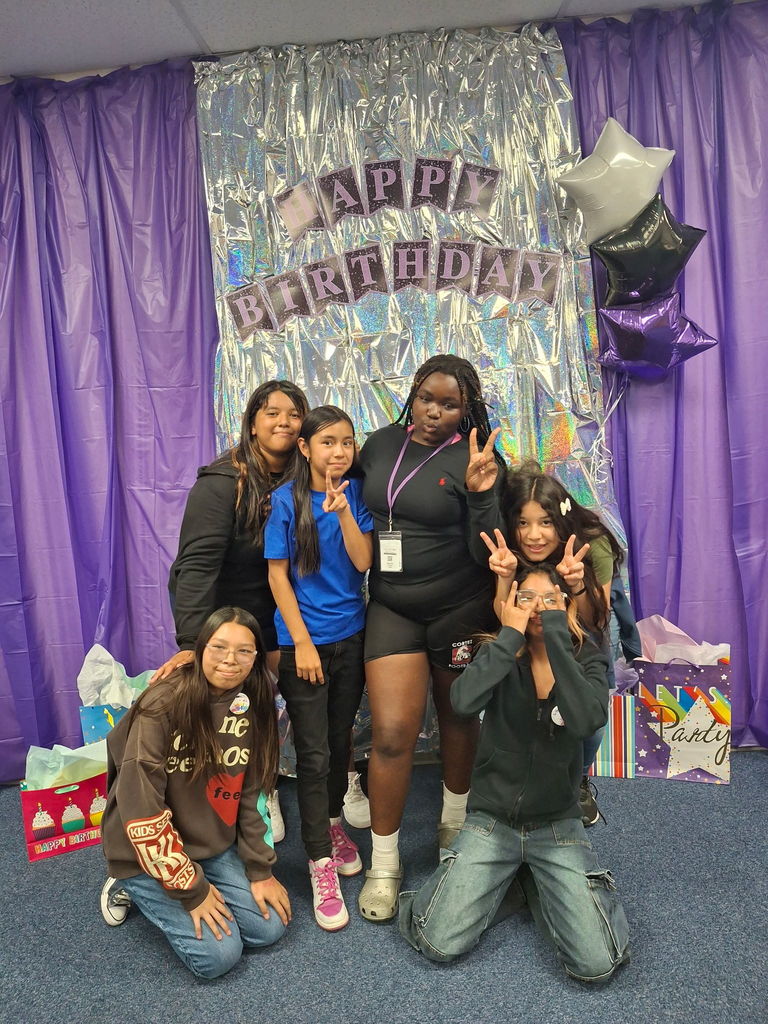 Students smiling, waving, and making peace signs while celebrating July birthdays with teachers at Estrella Middle School.