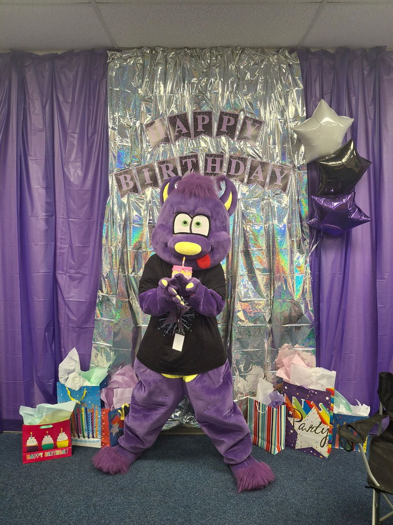 Purple and silver birthday decorations with balloons and a Happy Birthday banner at Estrella Middle School.