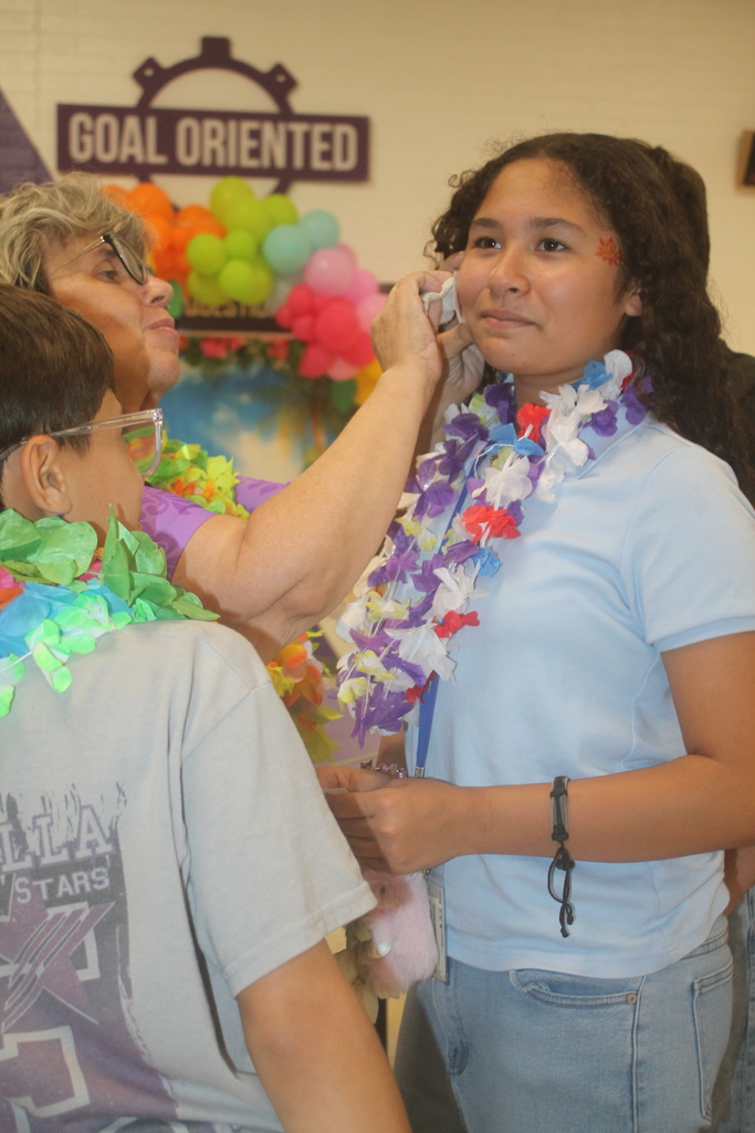 A student receiving a glitter tattoo while friends watch.