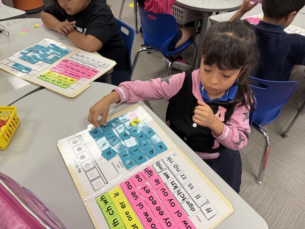 Students working with word mats that include letters, diagraphs, etc.