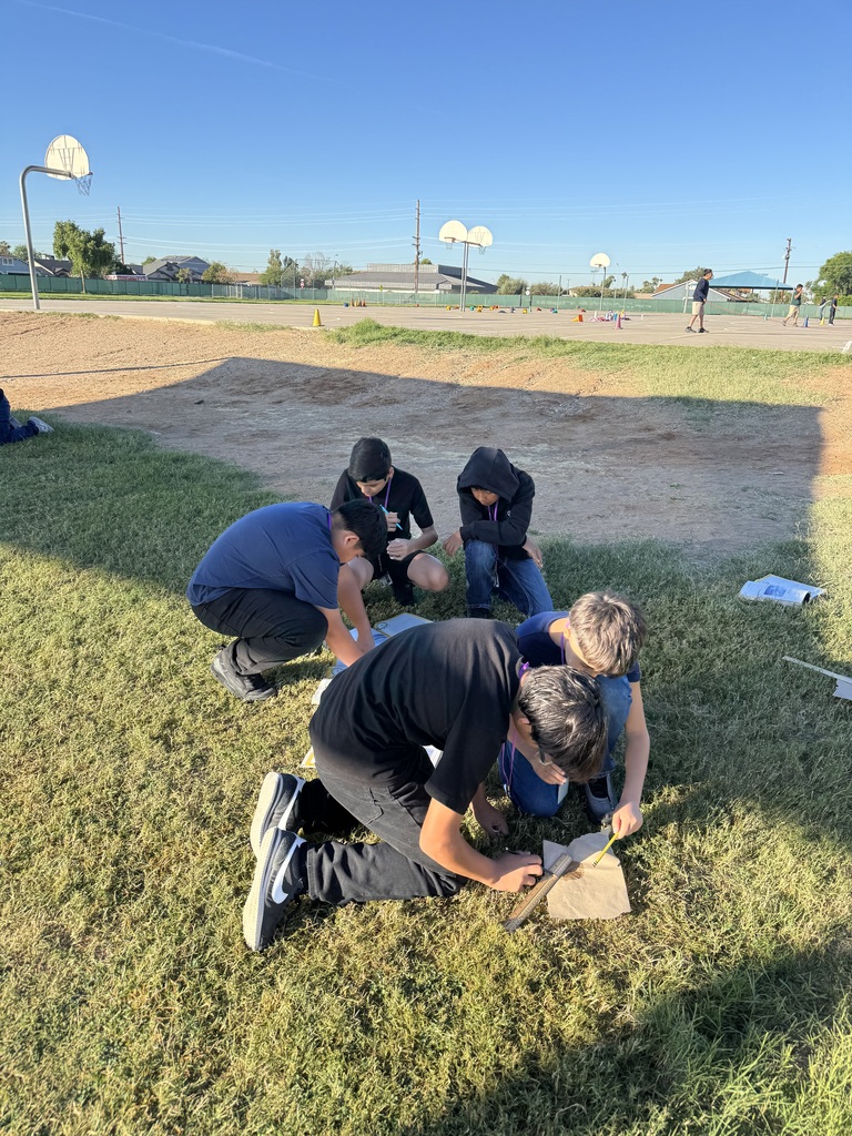 group of 5 male students working on a science lab outside