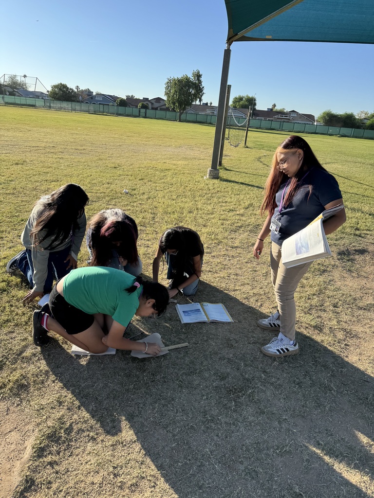 group of 5 female students working on a science lab outside