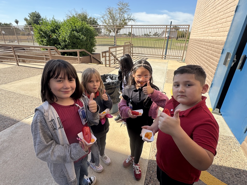 Students holding a thumbs up with their veggies in their other hand.