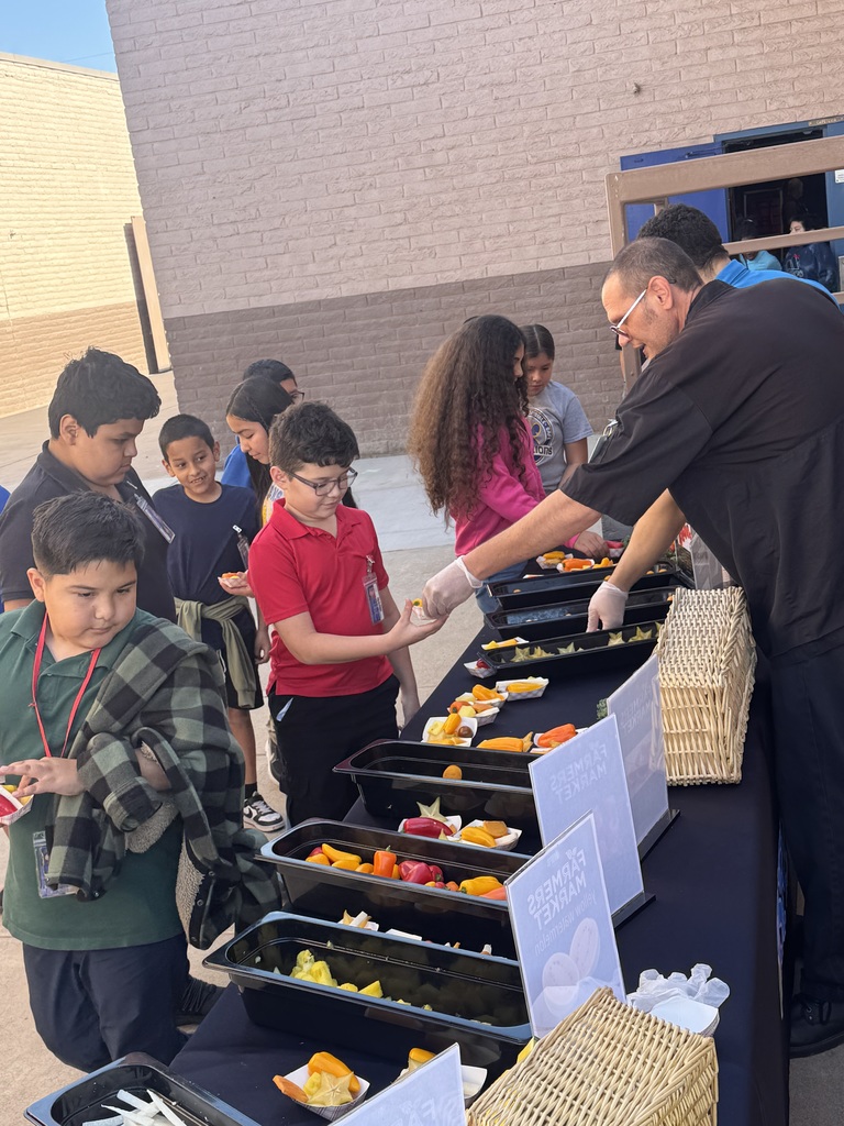 Table full of sunfruit, golden berries, and peppers. Workers handing them out to students.