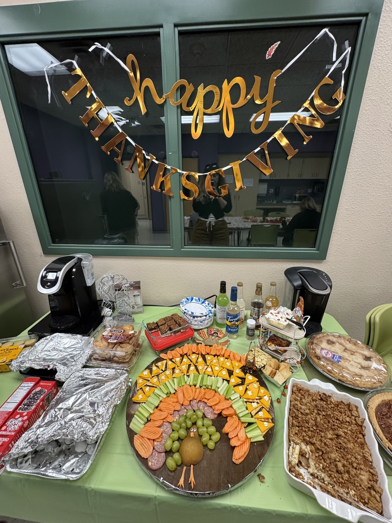 turkey-shaped charcuterie board, surrounded by desserts and a sign that reads happy thanksgiving