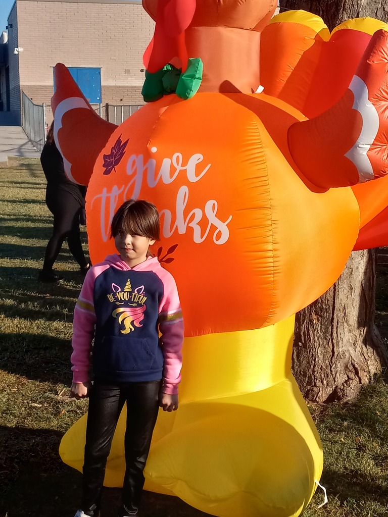 4th grade Turkey Trot Winner posing in front of an inflated turkey.