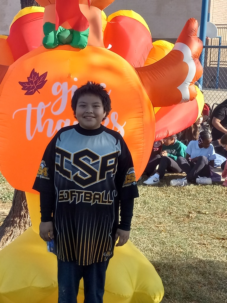 5th grade Turkey Trot Winner posing in front of an inflated turkey.