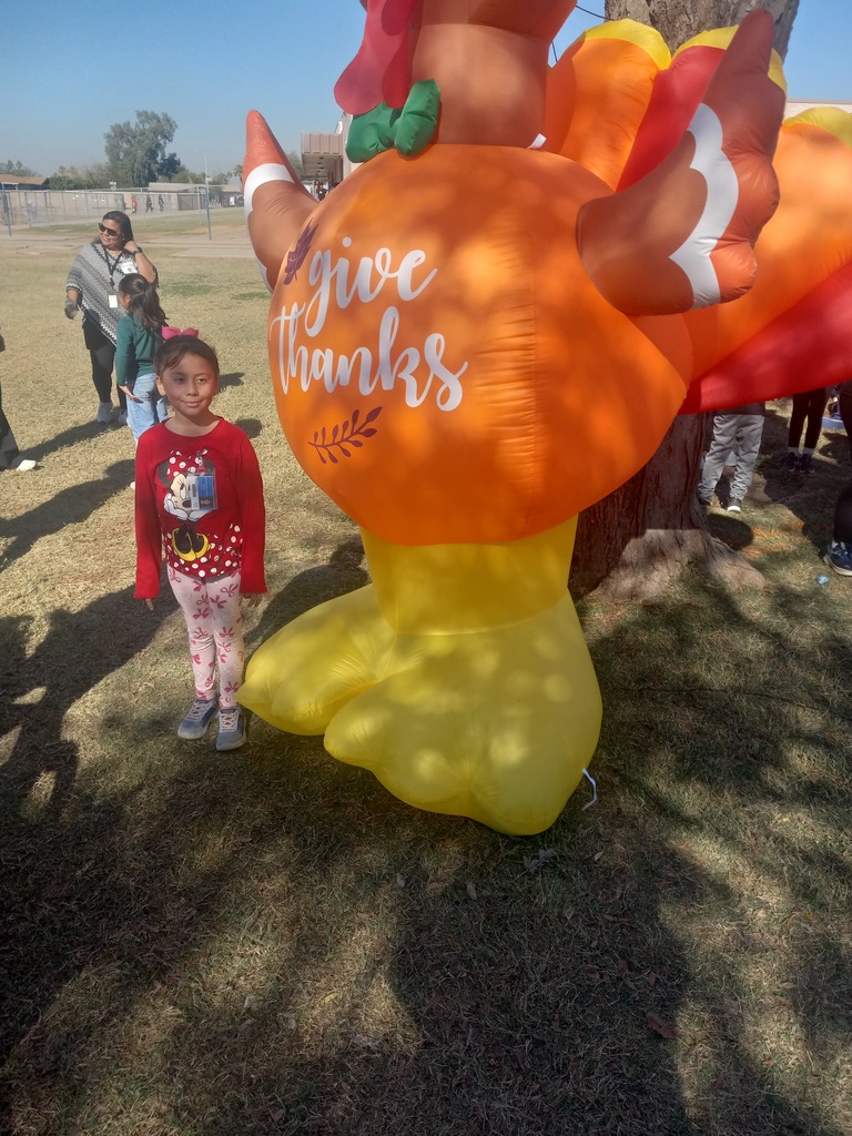 2nd grade Turkey Trot Winner posing in front of an inflated turkey.