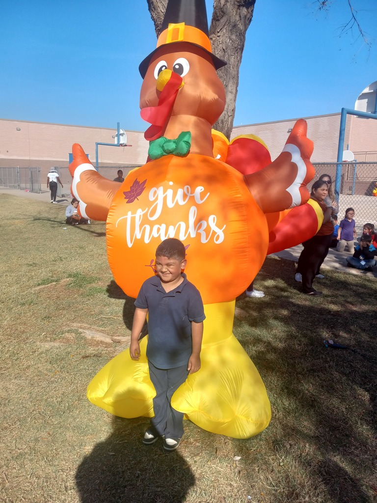 1st grade Turkey Trot Winner posing in front of an inflated turkey.