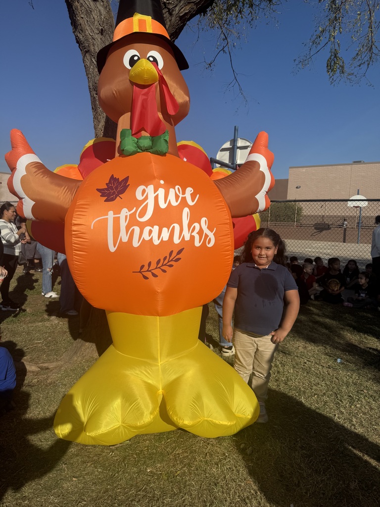 Kindergarten Turkey Trot Winner posing in front of an inflated turkey.