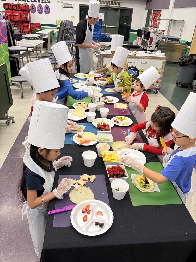 group of students in aprons and chef hats making lunch
