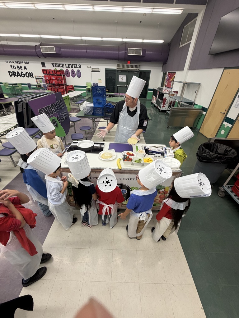 group of students in aprons and chef hats around the roving chef