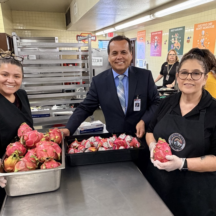 cafetería employees and superintendent holding dragon fruit