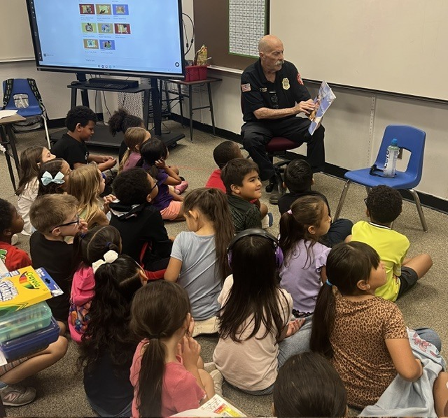 A volunteer reader reads a book to a class.
