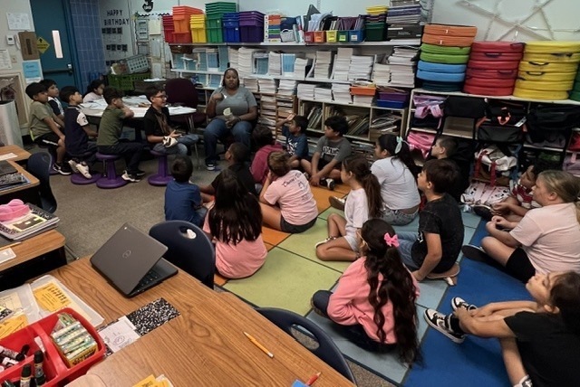 A volunteer reader reads a book to a class.