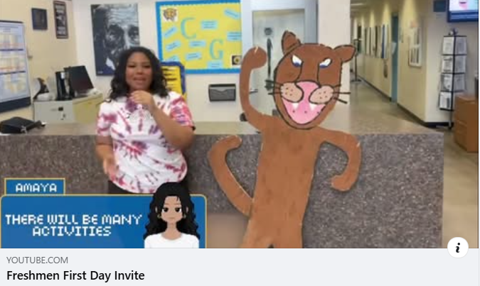student holding microphone in front office standing by a Cougar cutout