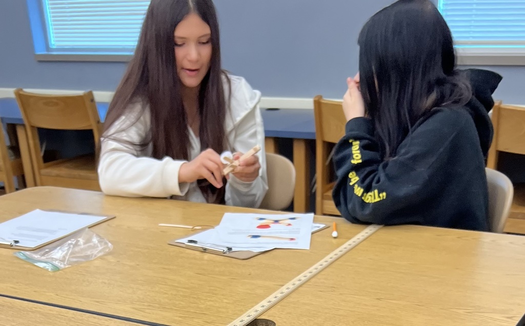 Two students working together to make a catapult out of popsicle sticks and rubber bands.