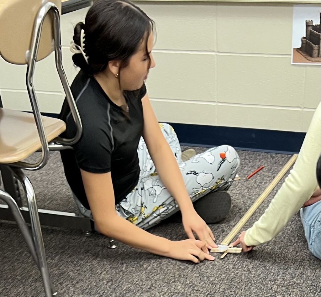 A student launching a candy pumpkin with a popsicle stick catapult.