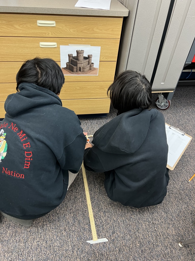 Two students launching a pumpkin with a popsicle stick catapult.