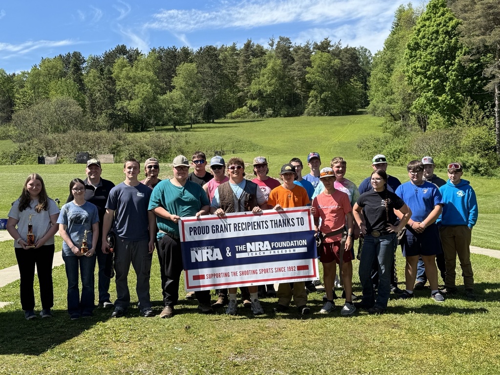 CLV Trap Club members (19) and coach holding a banner that says: "Proud Grant Recipients thanks to Friend of NRA & The NRA Foundation Teach Freedom. Supporting the Shooting Sports since 1992."
