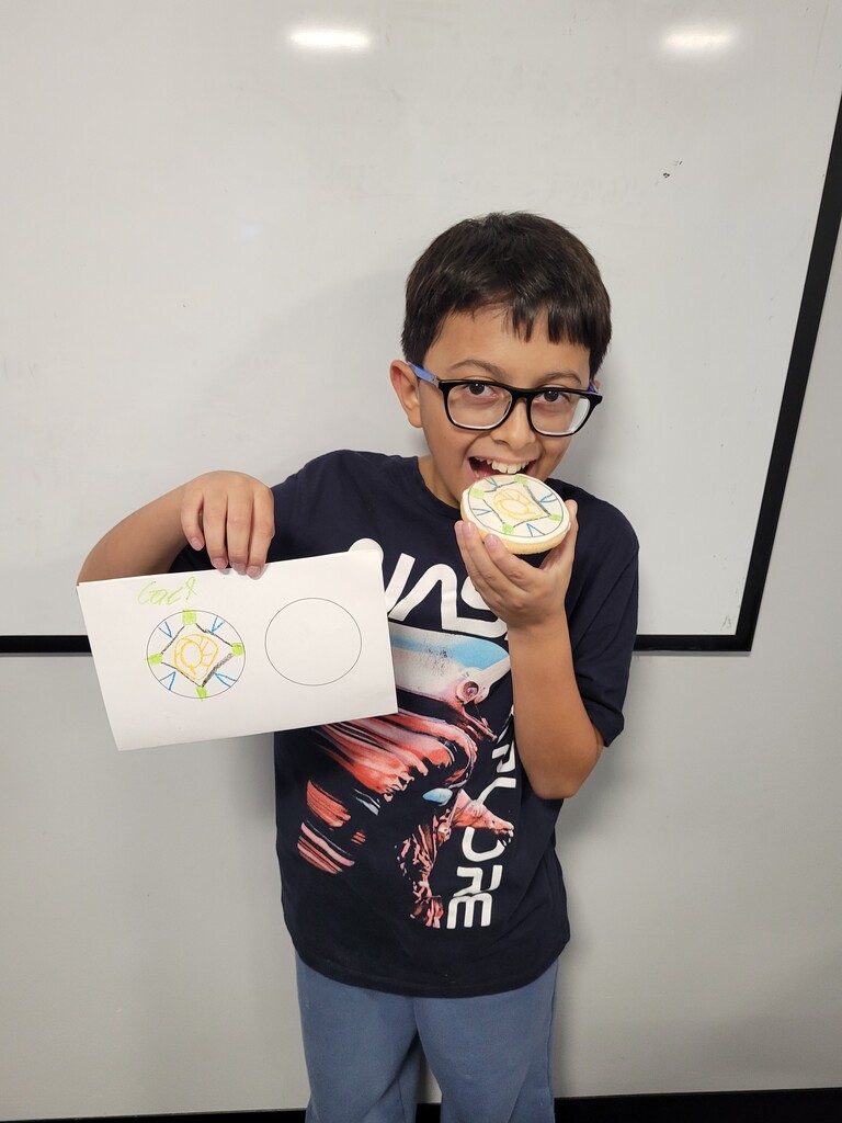 Student holding cookie with printed copy of drawing