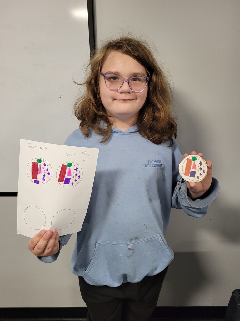 Student holding cookie with printed copy of drawing