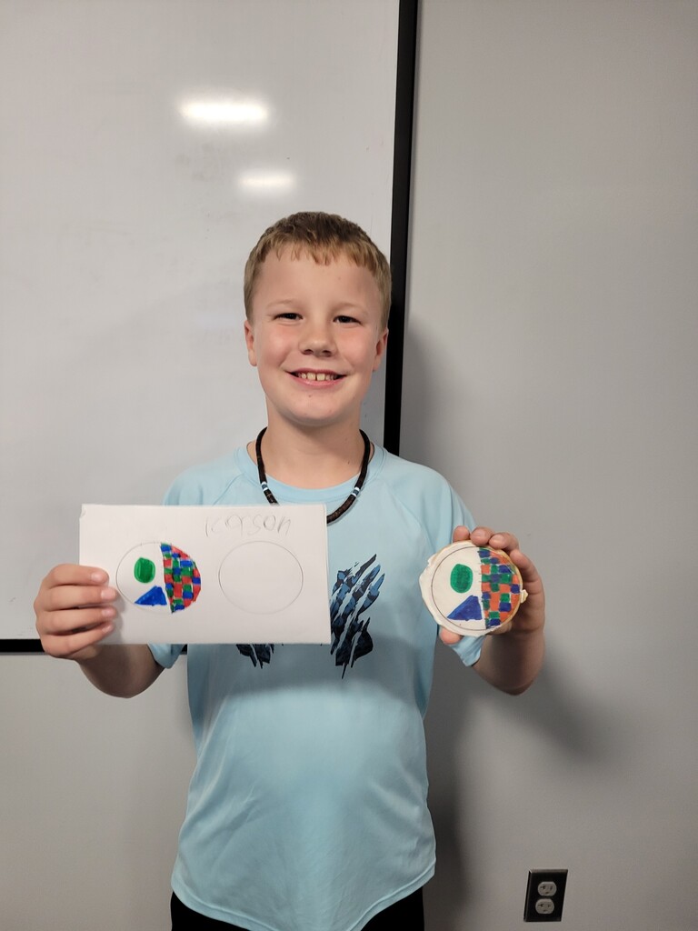 Student holding cookie with printed copy of drawing