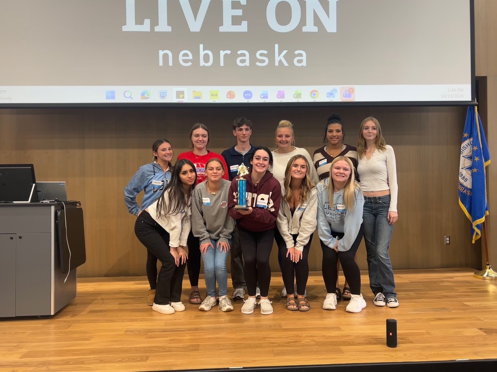 Eleven health science students grouped together on a stage, showing off trivia trophy