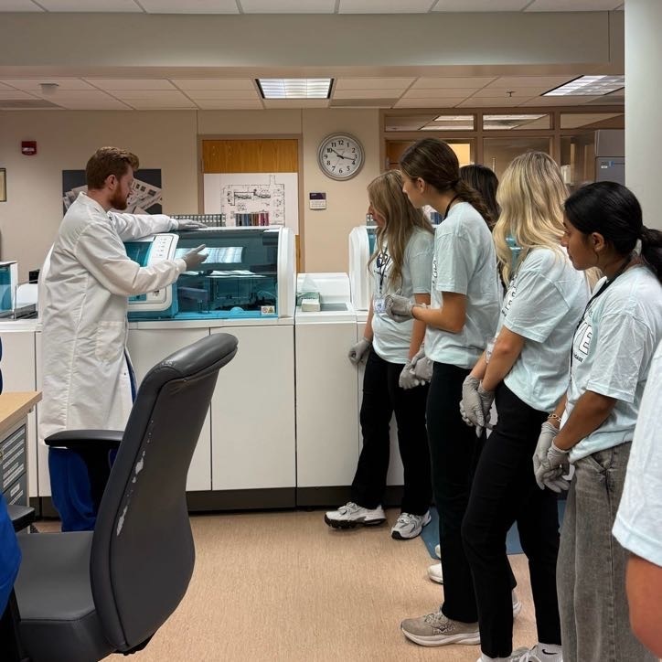 Dove Day students looking at machine while doctor explains its function