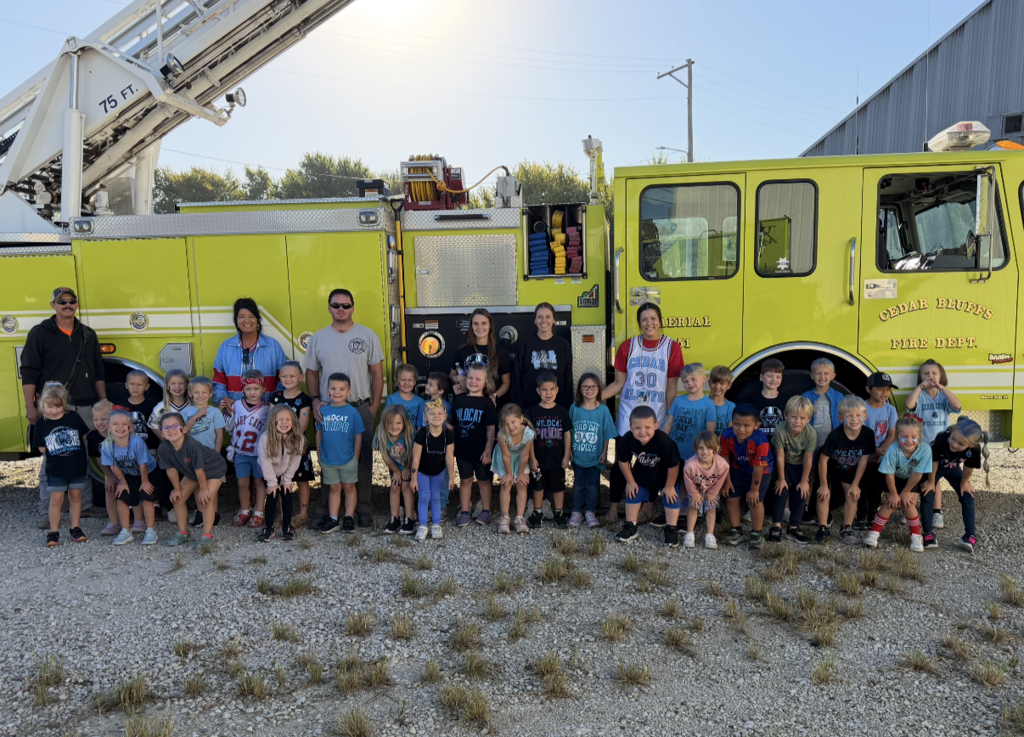 Kindergarten student positioned in front of firetruck posing for group photo