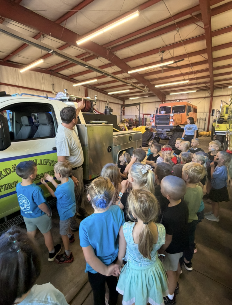 Firefighter explaining to kindergarten students the types of tools on their vehicles