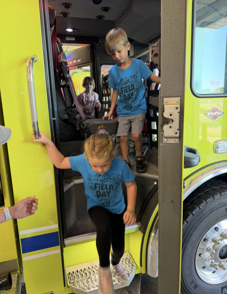 Two students exiting fire truck while another enters