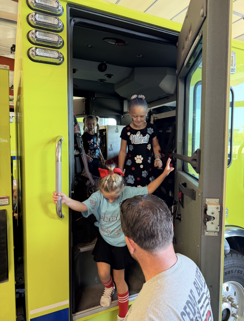 Firefighter helping two students out of fire truck
