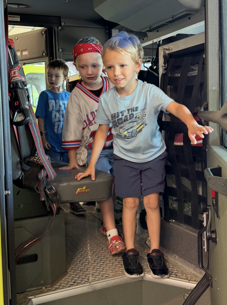 Three students looking at inside of fire truck