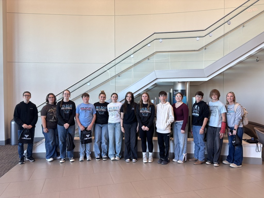 Twelve students and one teacher posed for group photo in front of staircase
