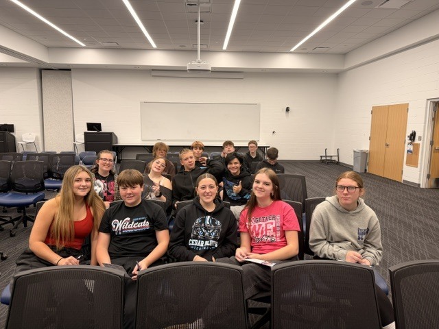 Fourteen students posed for group picture sitting in chairs