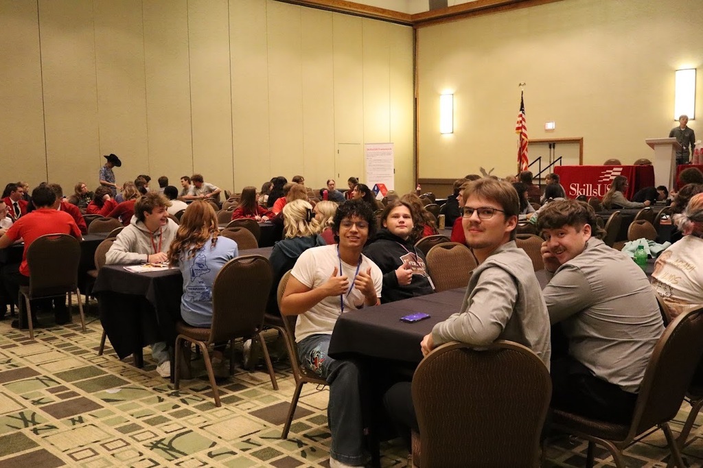 SkillsUSA students talking to other attendees while sitting at conference tables