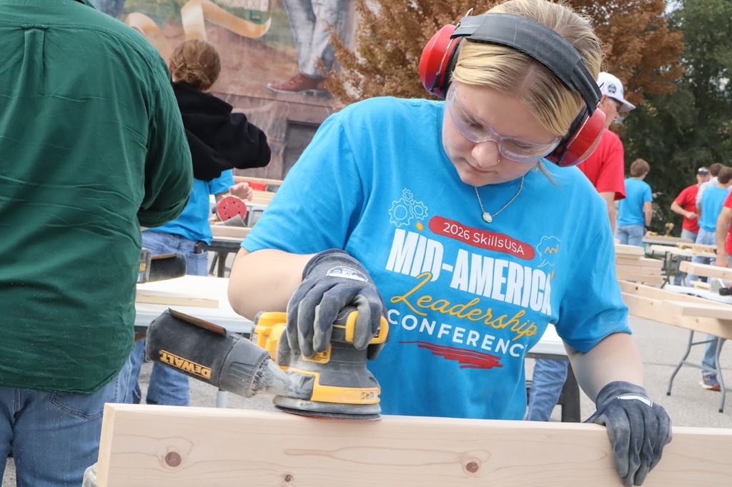 SkillsUSA student using power tool to sand a piece of wood