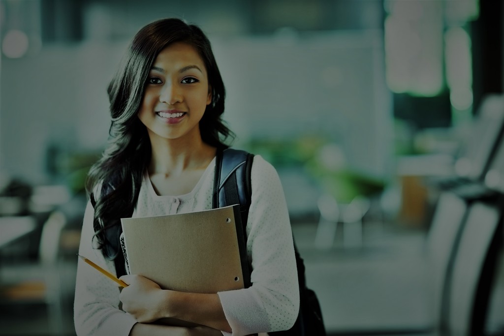 smiling teacher holding notebook and pencil