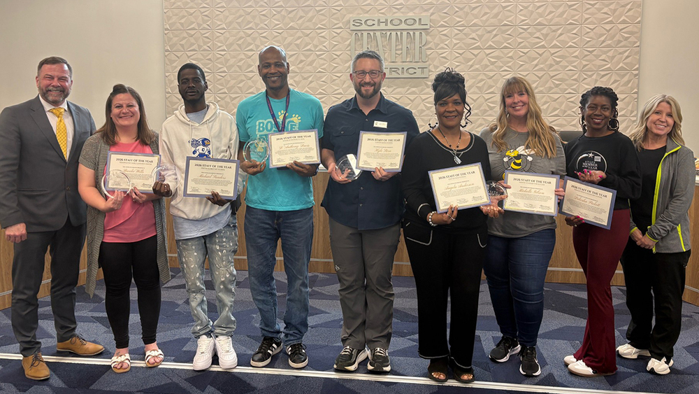 Staff of the Year honorees stand with the Superintendent and Board of Education Chair in front of the board dias.