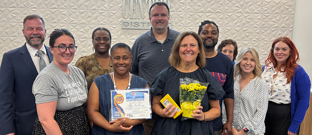 Group of smiling staff members stands in front of the board podium.