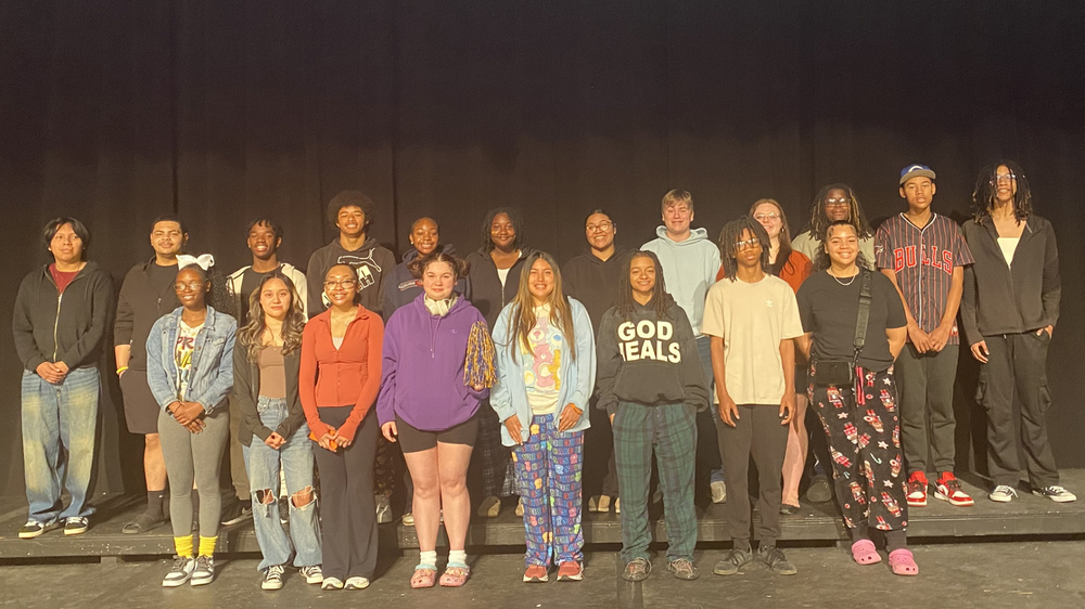 A group of young people standing together on stage, smiling for the audience.