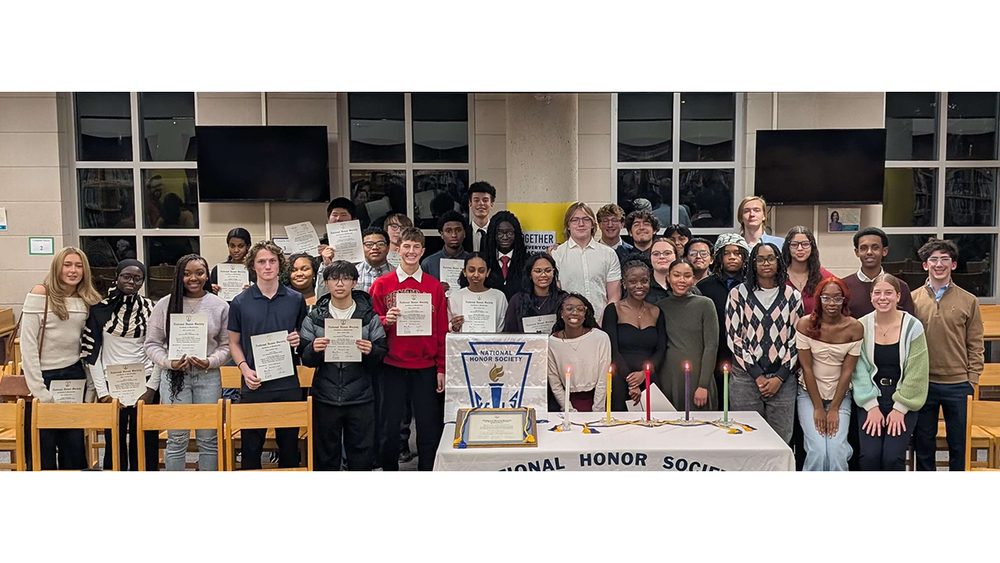 National Honor Society students stand in a group in the high school library.