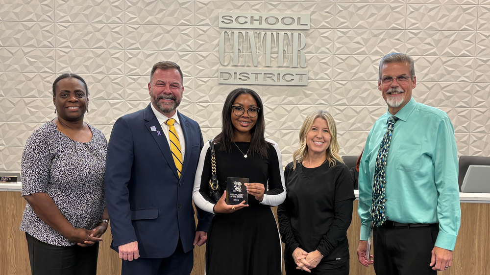 Five people stand in front of board dias.