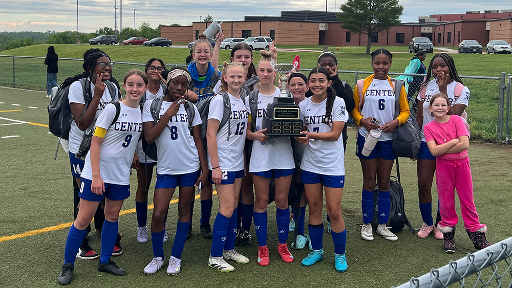 The girls soccer team proudly poses with their trophy, celebrating their victory in the end of season tournament.