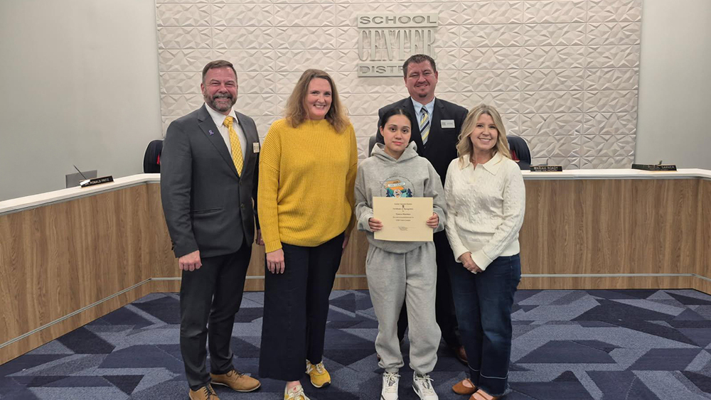 Superintendent, Coach, student Geneva Martinez, Director of Operations, and Board Chair stand in front of the board room.