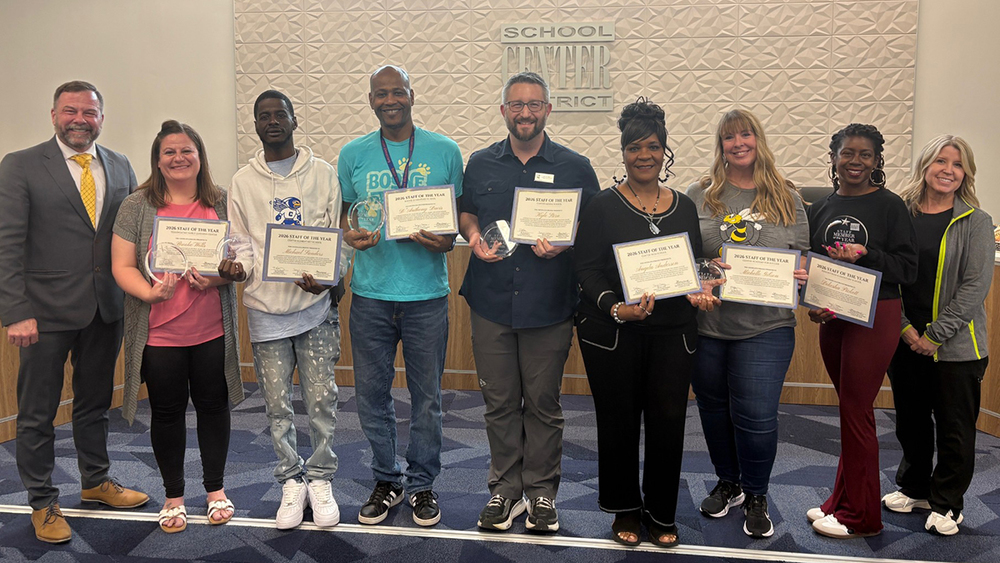 Staff of the Year honorees stand with the Superintendent and Board of Education Chair in front of the board dias.