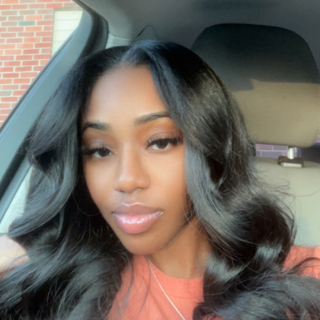 Woman with long, wavy black hair in the front seat of her car.