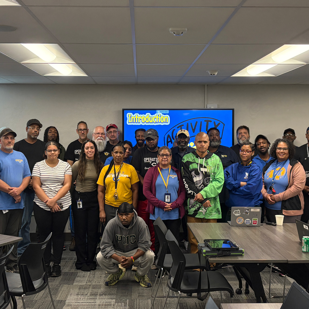 People standing in two lines in front of a blue tv screen, smiling for the camera.
