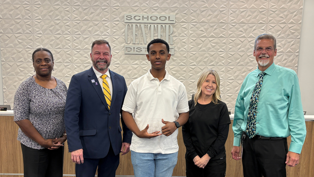 Five people stand in front of board dias.